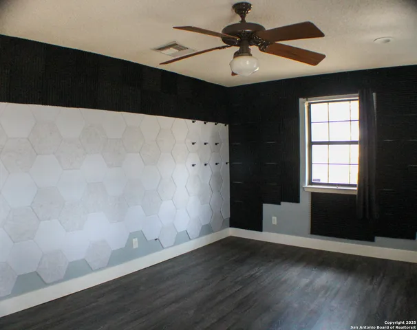 a view of wooden floor and a chandelier fan in a room
