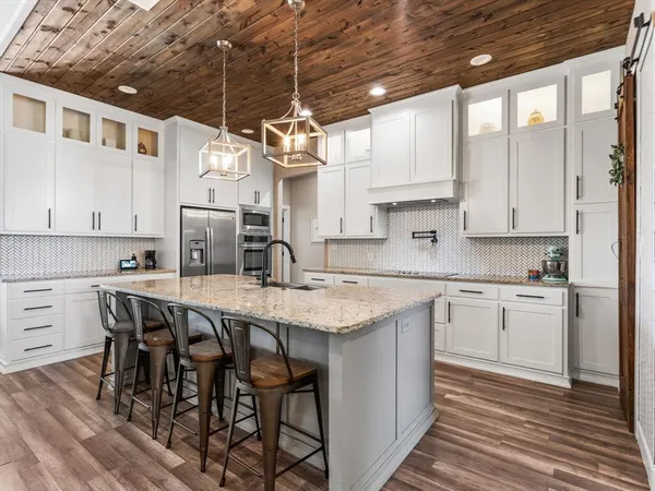 a kitchen with stainless steel appliances granite countertop a table chairs sink and cabinets