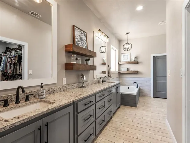 a large bathroom with a granite countertop double vanity sink a mirror and a bathtub