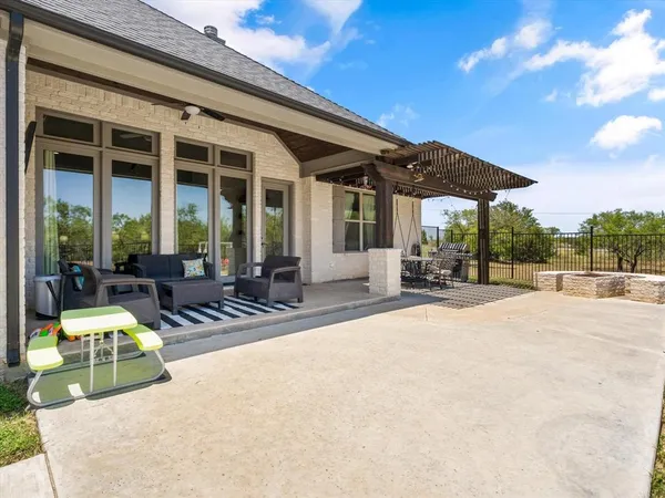 a view of a patio with a table and chairs under an umbrella with a small yard