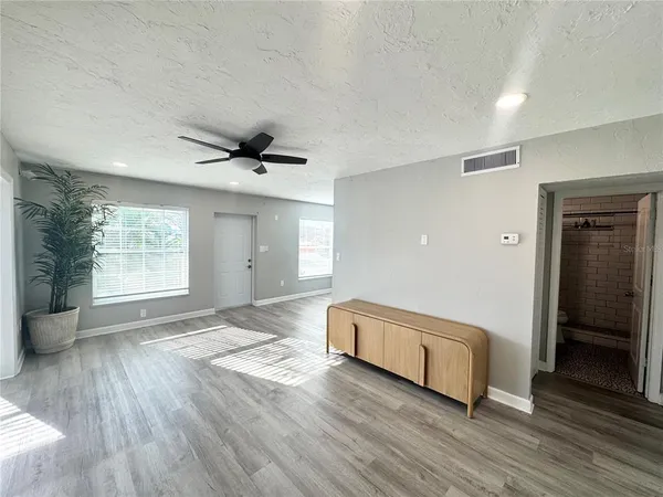 a kitchen with granite countertop a refrigerator oven a sink dishwasher and white cabinets with wooden floor