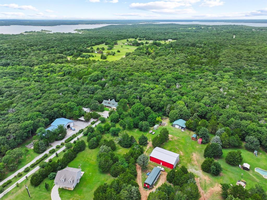 207 Paradise Park Road Pottsboro, TX 75076 - Photo 10 of 28 Expansive property featuring multiple structures, including a primary residence, a large blue-roofed building, and a red barn