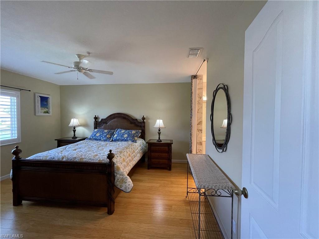 9009 Michael Circle, Unit 1110 Naples, FL 34113 - Photo 20 of 48 a bedroom with a bed and wooden floor