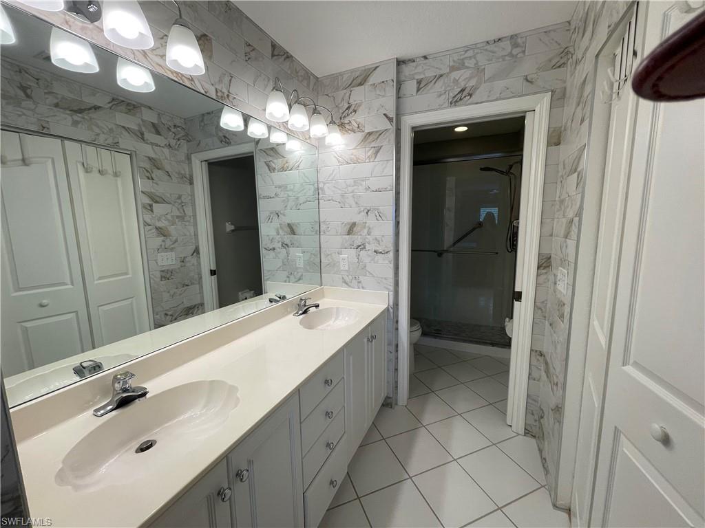 9009 Michael Circle, Unit 1110 Naples, FL 34113 - Photo 24 of 48 a bathroom with a double vanity sink mirror and shower