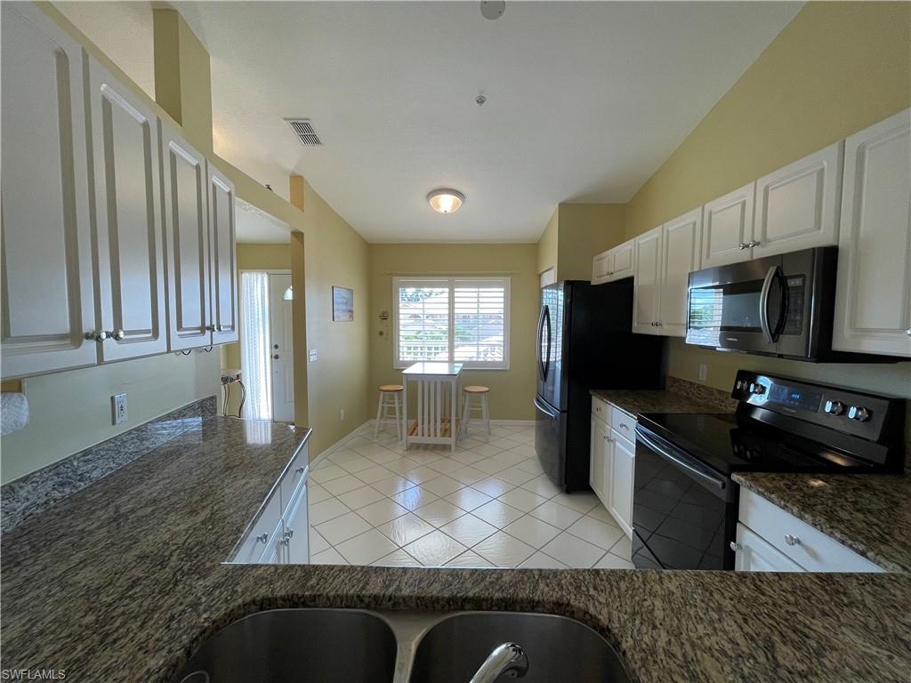 9009 Michael Circle, Unit 1110 Naples, FL 34113 - Photo 6 of 48 a kitchen with stainless steel appliances granite countertop a refrigerator a stove top oven and sink