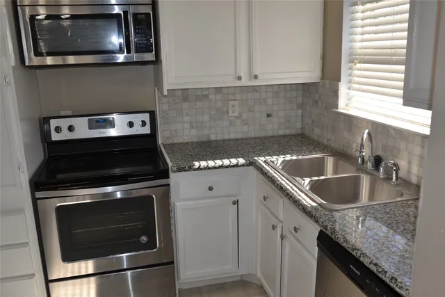 a kitchen with granite countertop a stove sink and cabinets