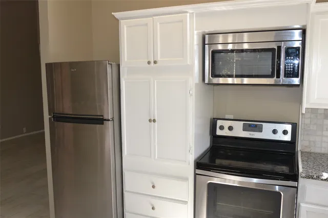a kitchen with white cabinets and stainless steel appliances