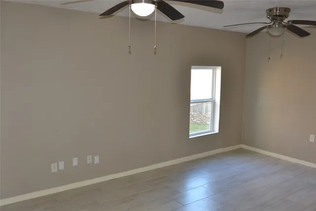 an empty room with a window and a ceiling fan