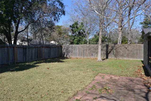 a backyard with wooden fence and a large tree