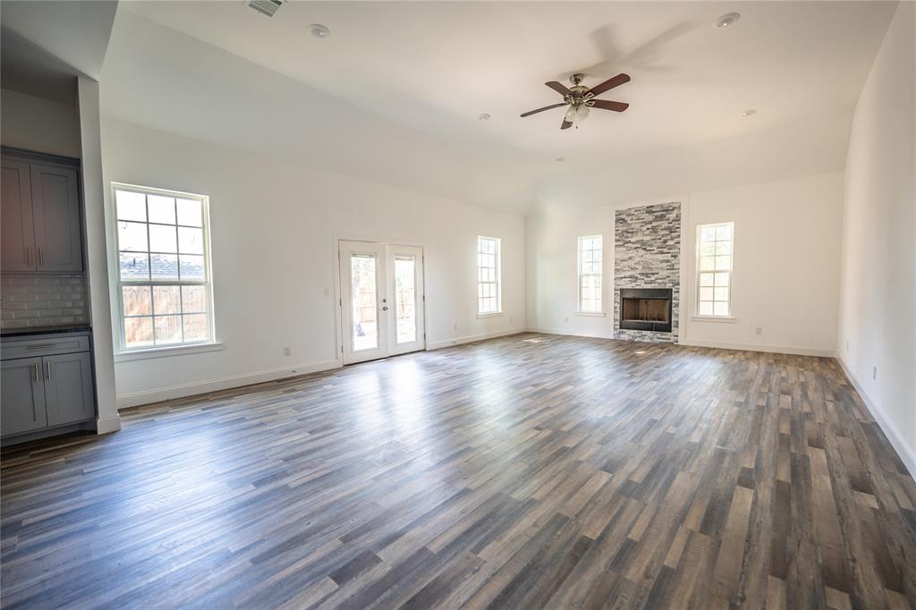 1408 Spinnaker Lane Azle, TX 76020 - Photo 7 of 8 Unfurnished living room with a ceiling fan, a fireplace, dark wood-style flooring, french doors, and lofted ceiling