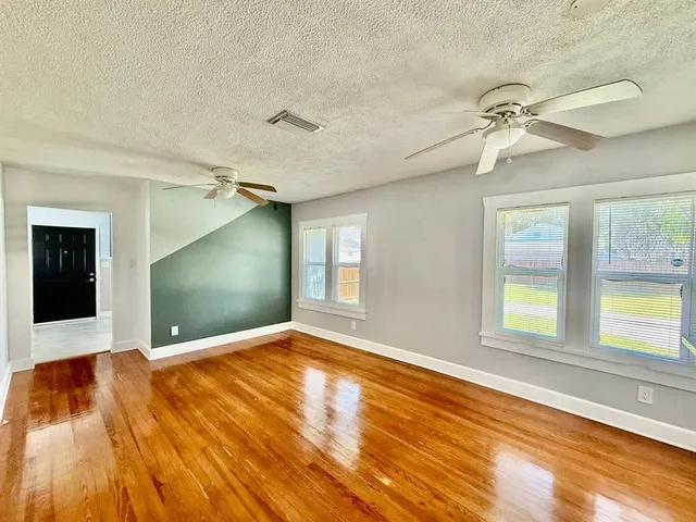 a view of an empty room with window and wooden floor