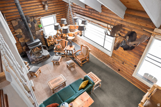 4725 Pine Ridge Road Evanston, UT 82930 - Photo 39 of 82 Spacious log cabin interior featuring a stone fireplace with wood stove, exposed log walls, high vaulted ceilings, and large windows