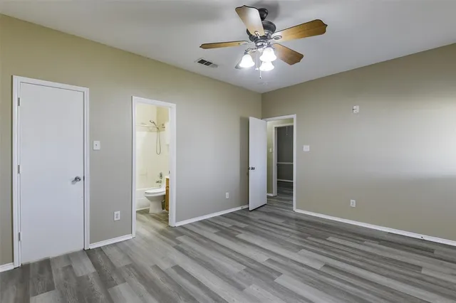 wooden floor in an empty room with a chandelier fan
