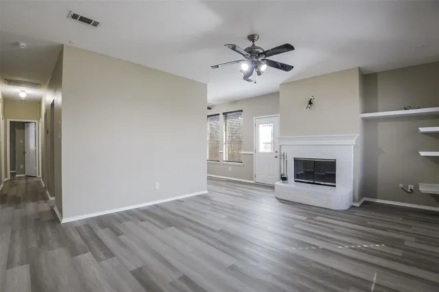 a view of a livingroom with a fireplace a ceiling fan and wooden floor