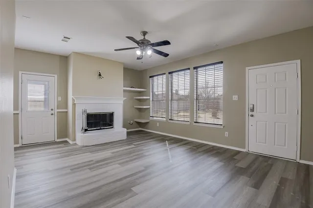 a view of a livingroom with a ceiling fan fireplace and wooden floor