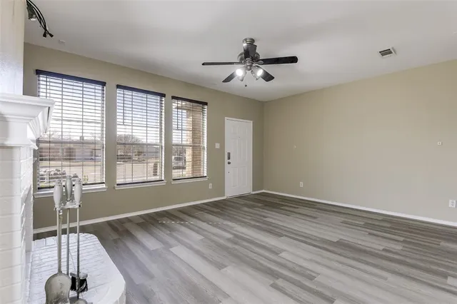 a view of an empty room with a window and wooden floor