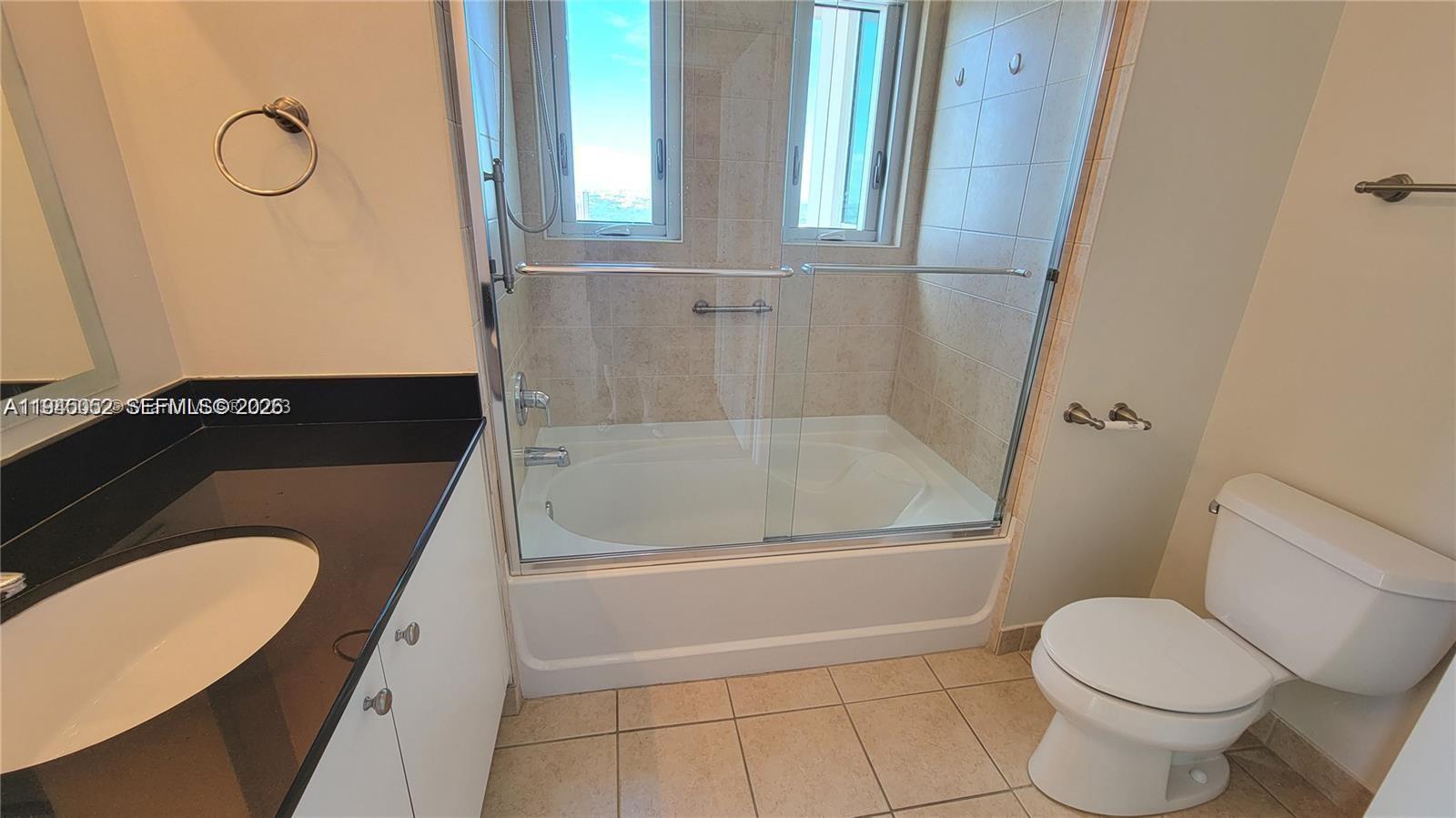 9055 Southwest 73rd Court, Unit 2503 Miami, FL 33156 - Photo 5 of 11 a bathroom with a granite countertop sink toilet and shower