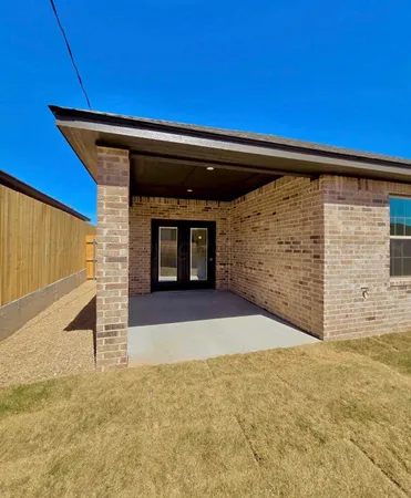 a view of an empty room with kitchen and window