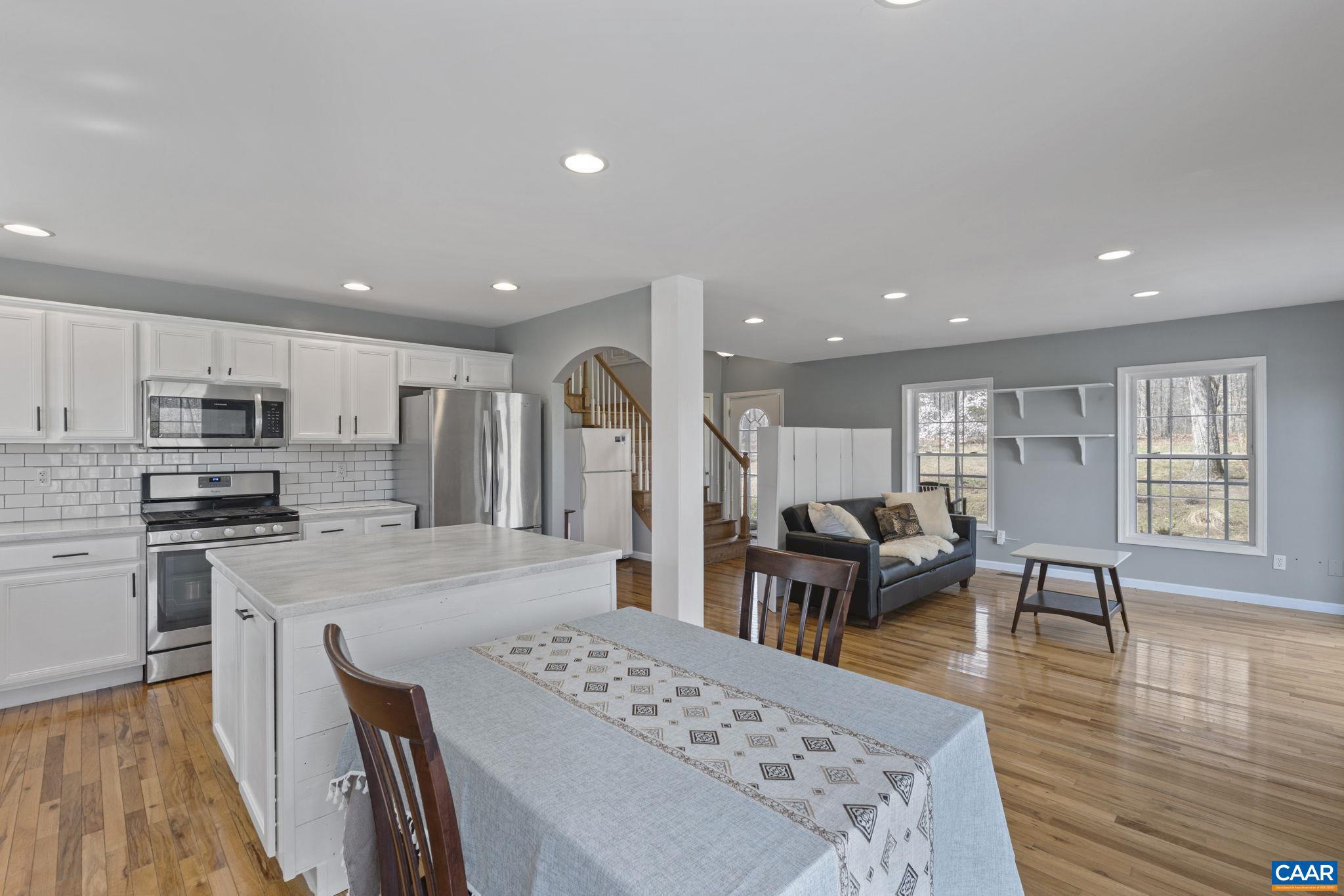 379 Fox Ridge Lane Palmyra, VA 22963 - Photo 16 of 42 a large kitchen with stainless steel appliances kitchen island granite countertop a refrigerator a stove a dining table and chairs with wooden floor