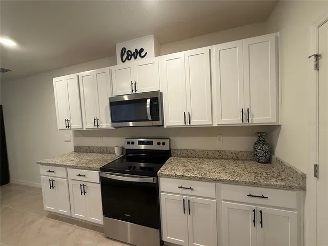 a kitchen with granite countertop white cabinets and black appliances