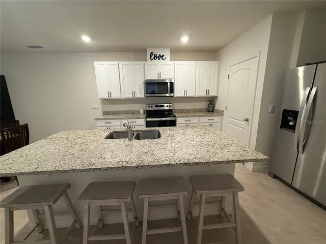 a kitchen with stainless steel appliances granite countertop a table chairs sink refrigerator and microwave