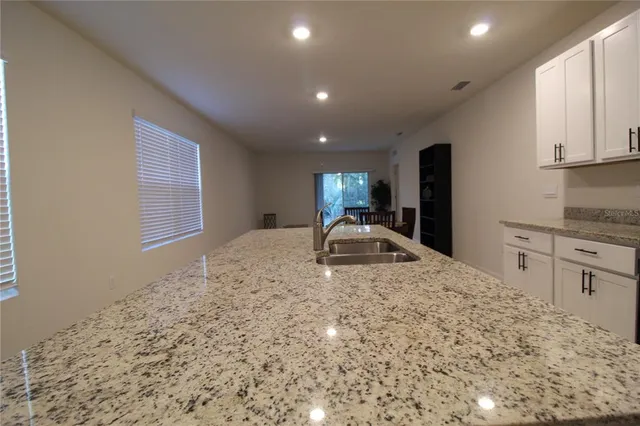 a kitchen with granite countertop white cabinets and a stove with wooden floor