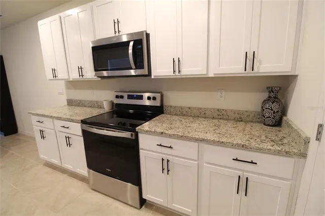 a kitchen with granite countertop a sink chairs and microwave