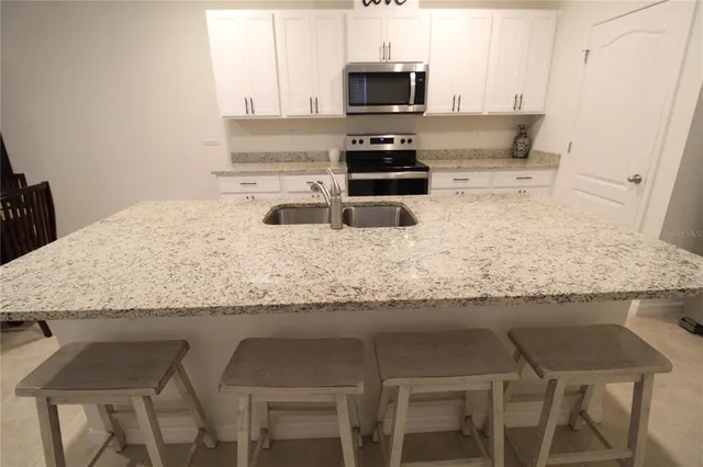 a kitchen with granite countertop a sink stove and refrigerator