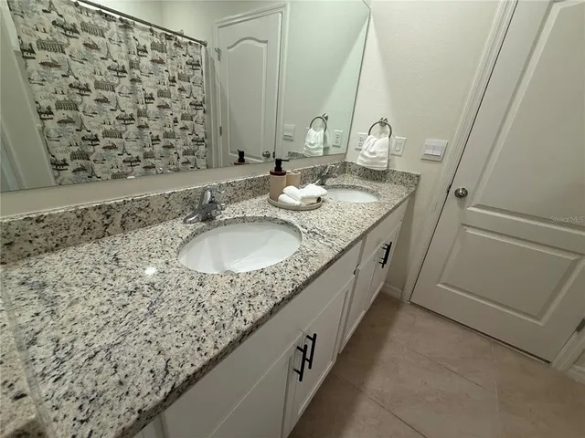 a bathroom with a granite countertop sink a mirror and a shower