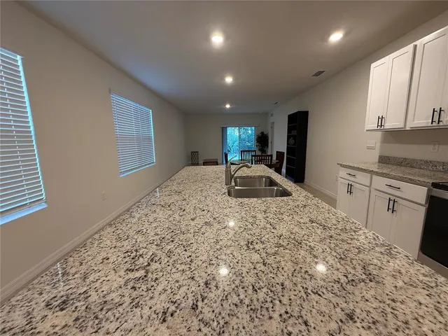 a view of a kitchen with kitchen island a sink wooden floor and a refrigerator