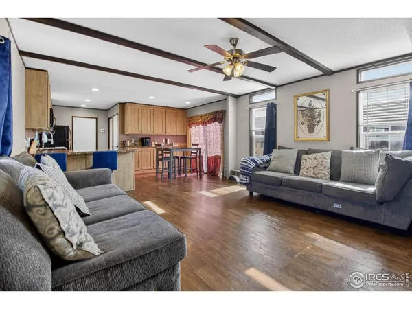a living room with furniture kitchen view and a wooden floor