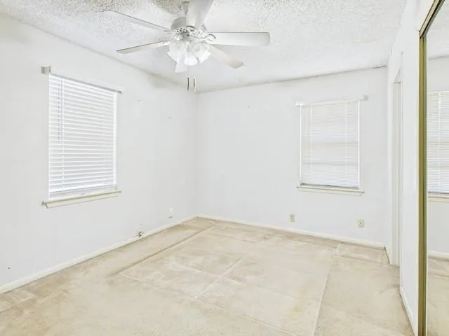 an empty room with windows and fan