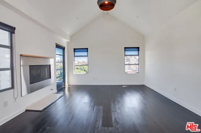 an empty room with wooden floor fireplace and windows