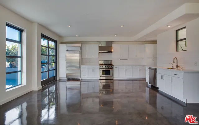 a kitchen with granite countertop a refrigerator and white cabinets