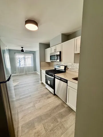 a large white kitchen with stainless steel appliances a sink a stove a microwave a refrigerator a counter top space and cabinets