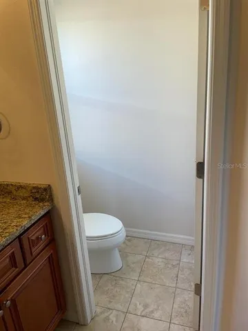 a bathroom with a granite countertop toilet and a sink