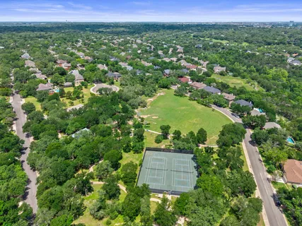 an aerial view of a residential houses with outdoor space and trees all around