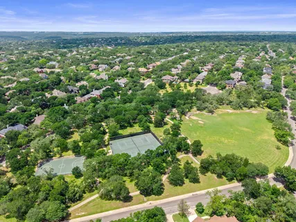 an aerial view of residential houses with outdoor space and trees all around