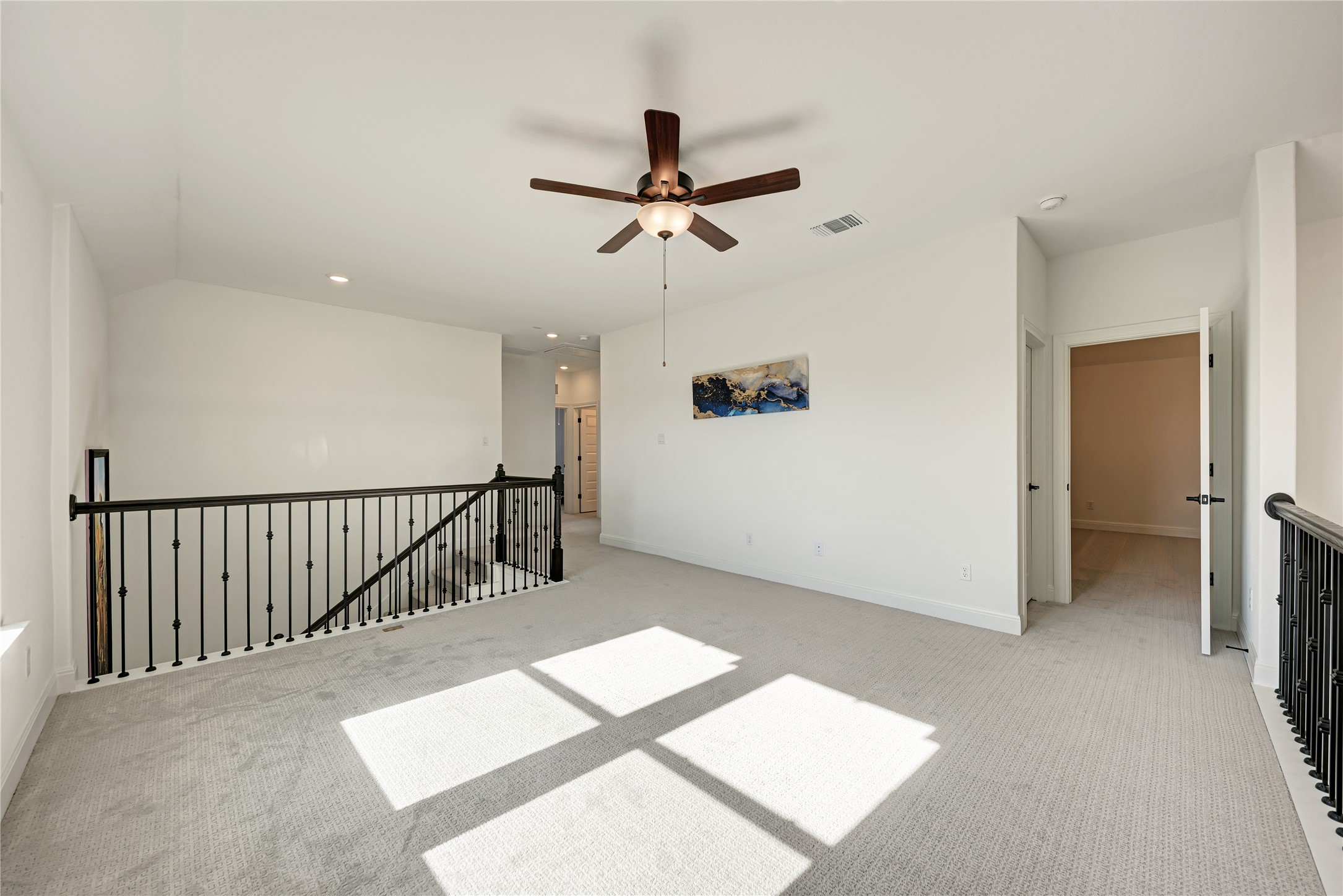316 Regatta Trail Leander, TX 78641 - Photo 26 of 39 Spacious carpeted bonus room featuring a ceiling fan with light, recessed lighting, and a black wrought iron railing overlooking the staircase
