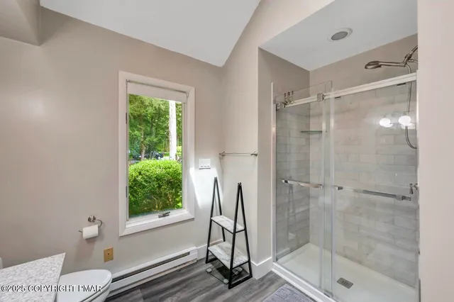a bathroom with a glass shower door and a window