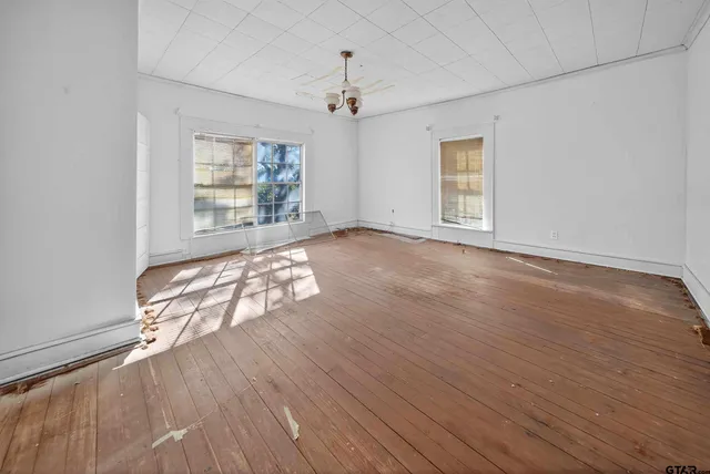 an empty room with wooden floor and windows