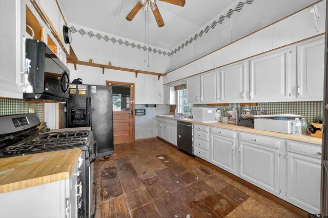 a kitchen with stainless steel appliances granite countertop a refrigerator a stove and white cabinets with wooden floor