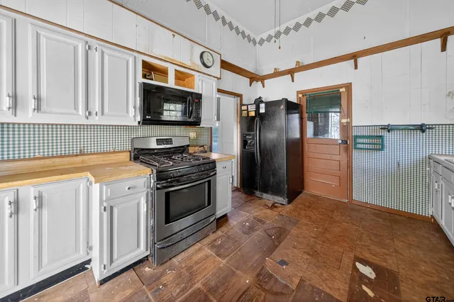 a kitchen with stainless steel appliances granite countertop a refrigerator a stove and a sink with wooden floors