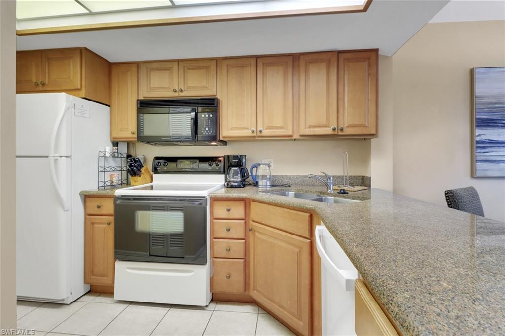 600 Neapolitan Way, Unit 345 Naples, FL 34103 - Photo 18 of 43 Kitchen featuring white appliances, a sink, and light tile patterned floors