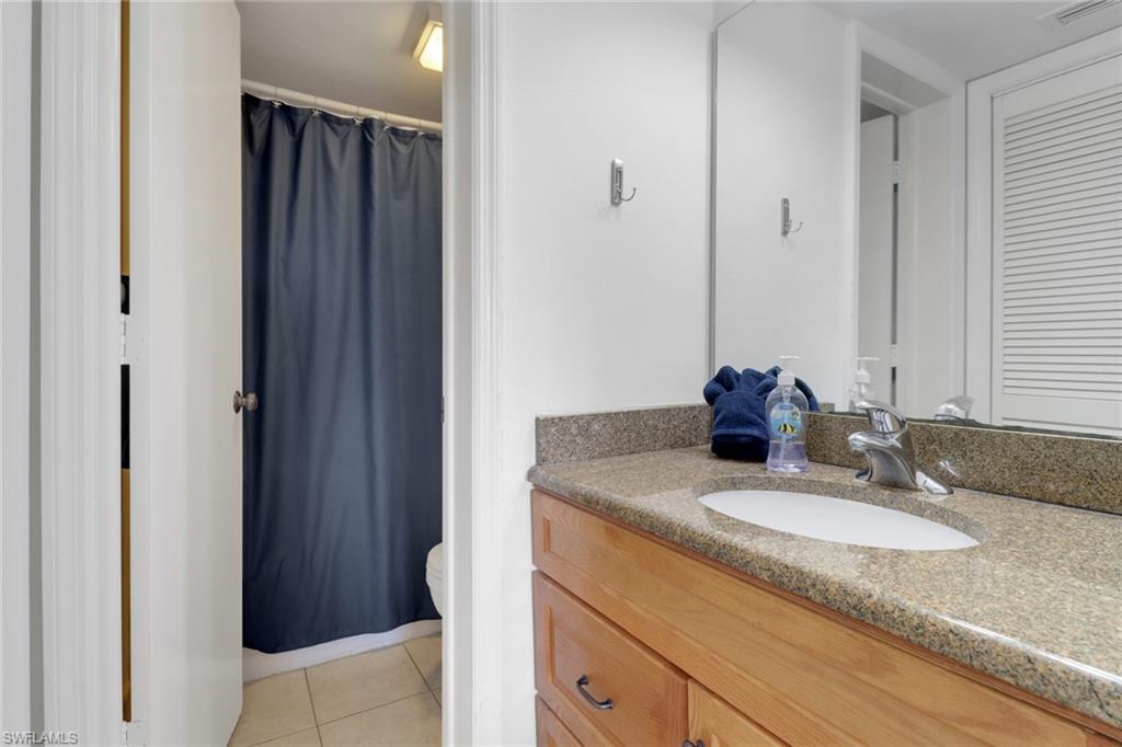 600 Neapolitan Way, Unit 345 Naples, FL 34103 - Photo 25 of 43 Full bath featuring tile patterned floors, toilet, vanity, and a shower with shower curtain