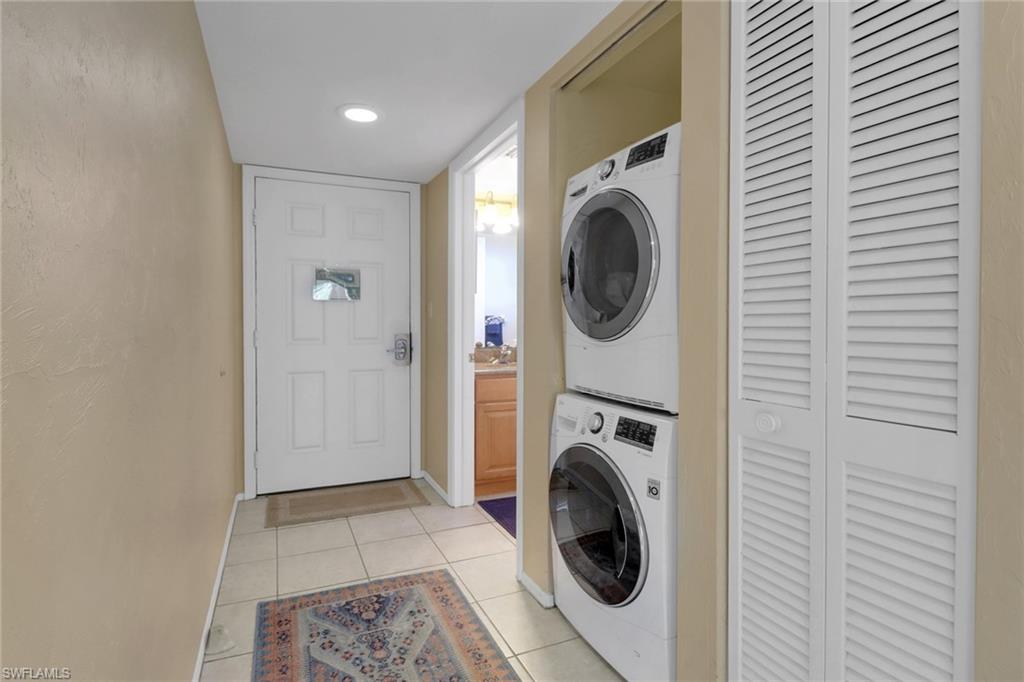 600 Neapolitan Way, Unit 345 Naples, FL 34103 - Photo 27 of 43 Laundry room featuring estacked washer and dryer, light tile patterned floors, baseboards, and recessed lighting