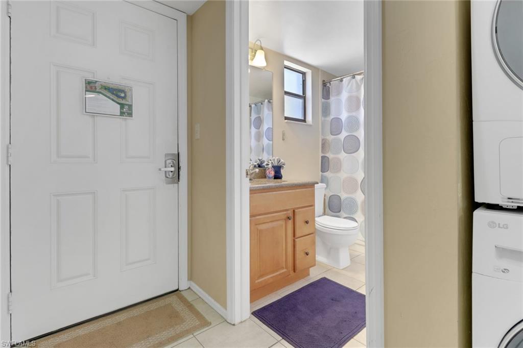 600 Neapolitan Way, Unit 345 Naples, FL 34103 - Photo 28 of 43 Full bathroom with stacked washer and clothes dryer, tile patterned flooring, vanity, toilet, and a shower with shower curtain