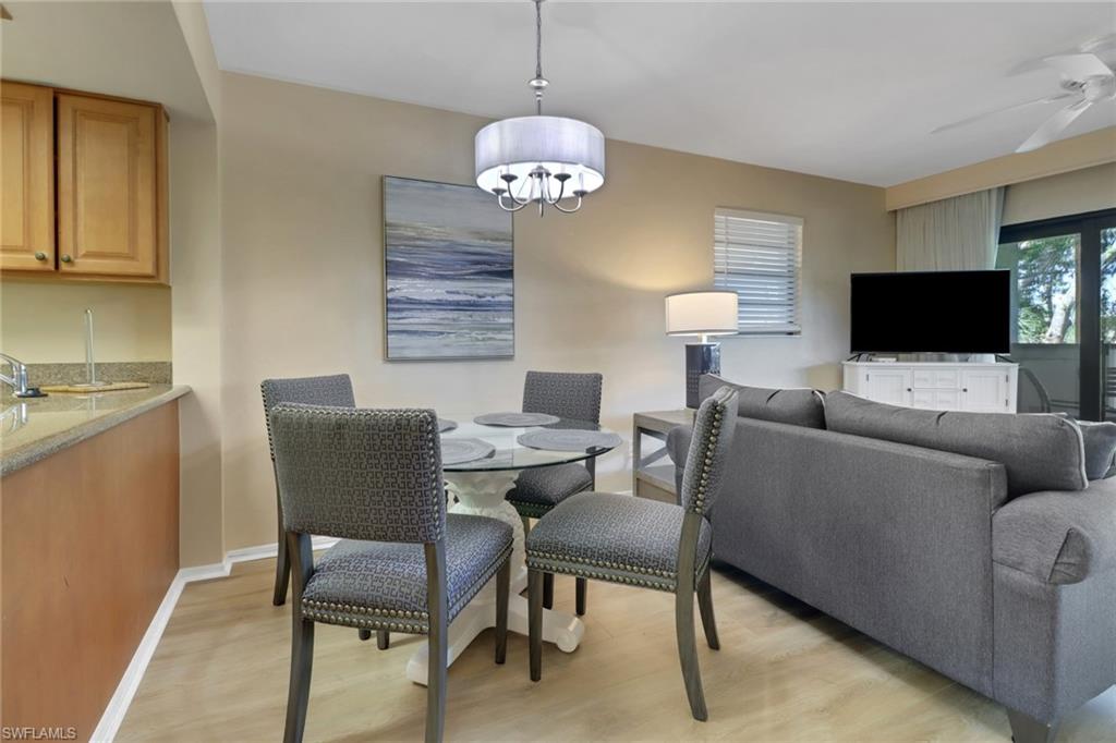 Dining room featuring light wood-style flooring, baseboards, ceiling fan, a chandelier, and bar area