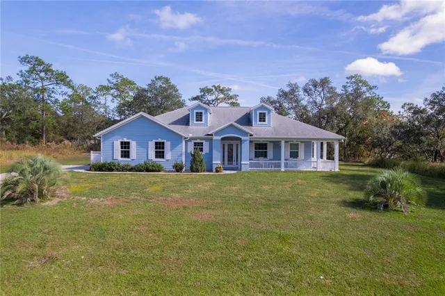 a view of a big house with a big yard and large trees