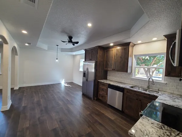 a kitchen with stainless steel appliances granite countertop a sink a stove and a wooden floors